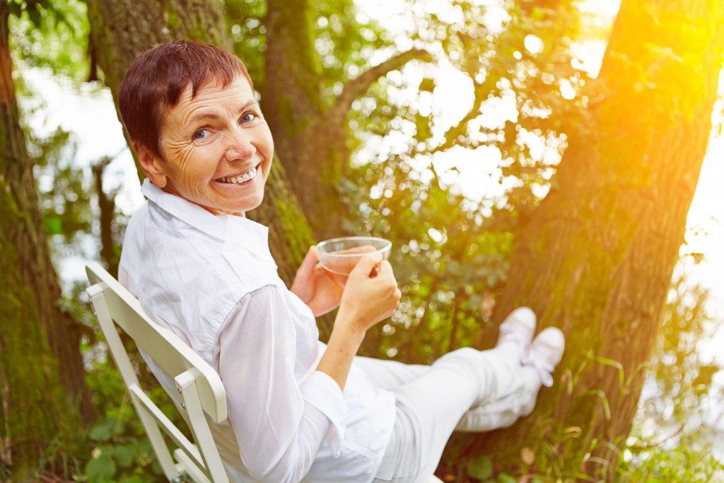 grandmother relaxing beside trees and drinking tea