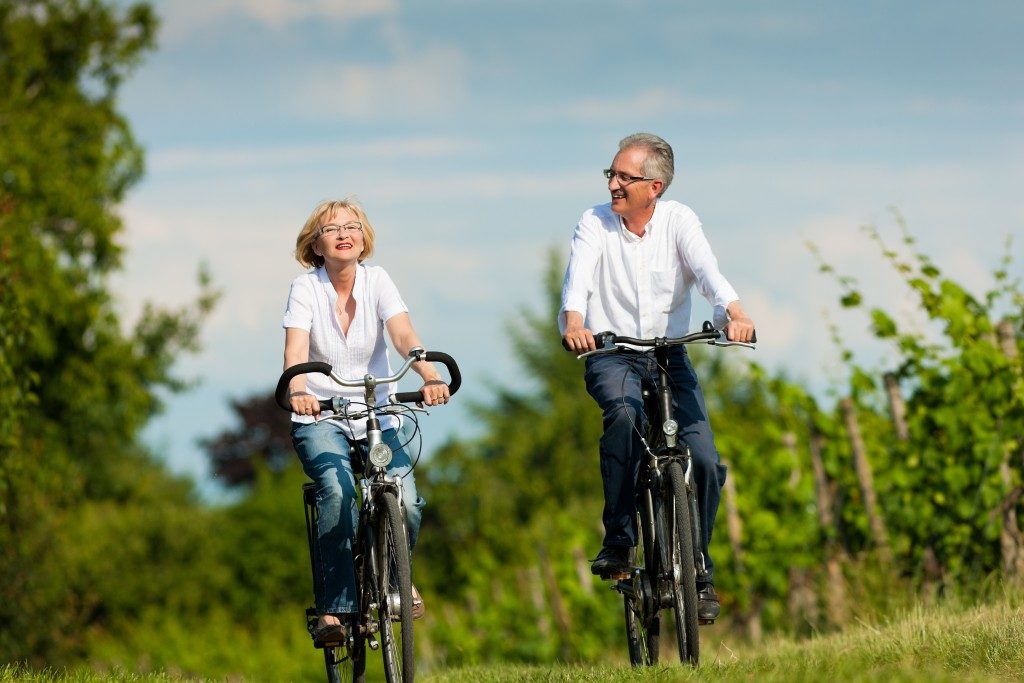 two senior couple riding bikes by the forest