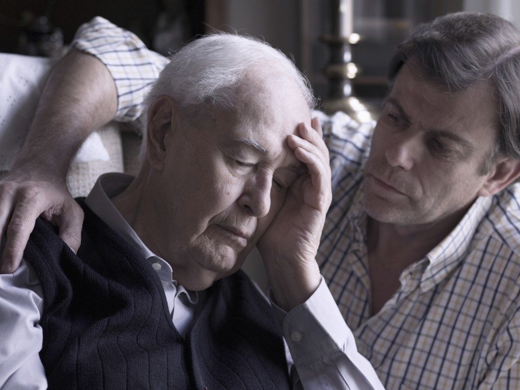 Elderly man comforted by his son