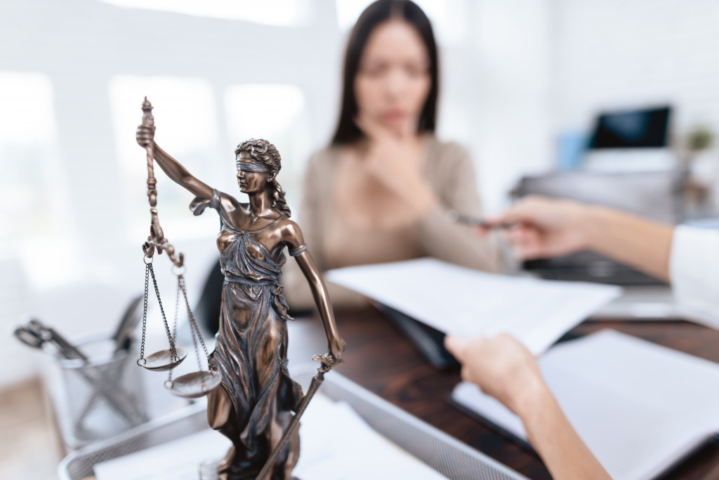Lady Justice statue inside an office while woman and lawyer talks